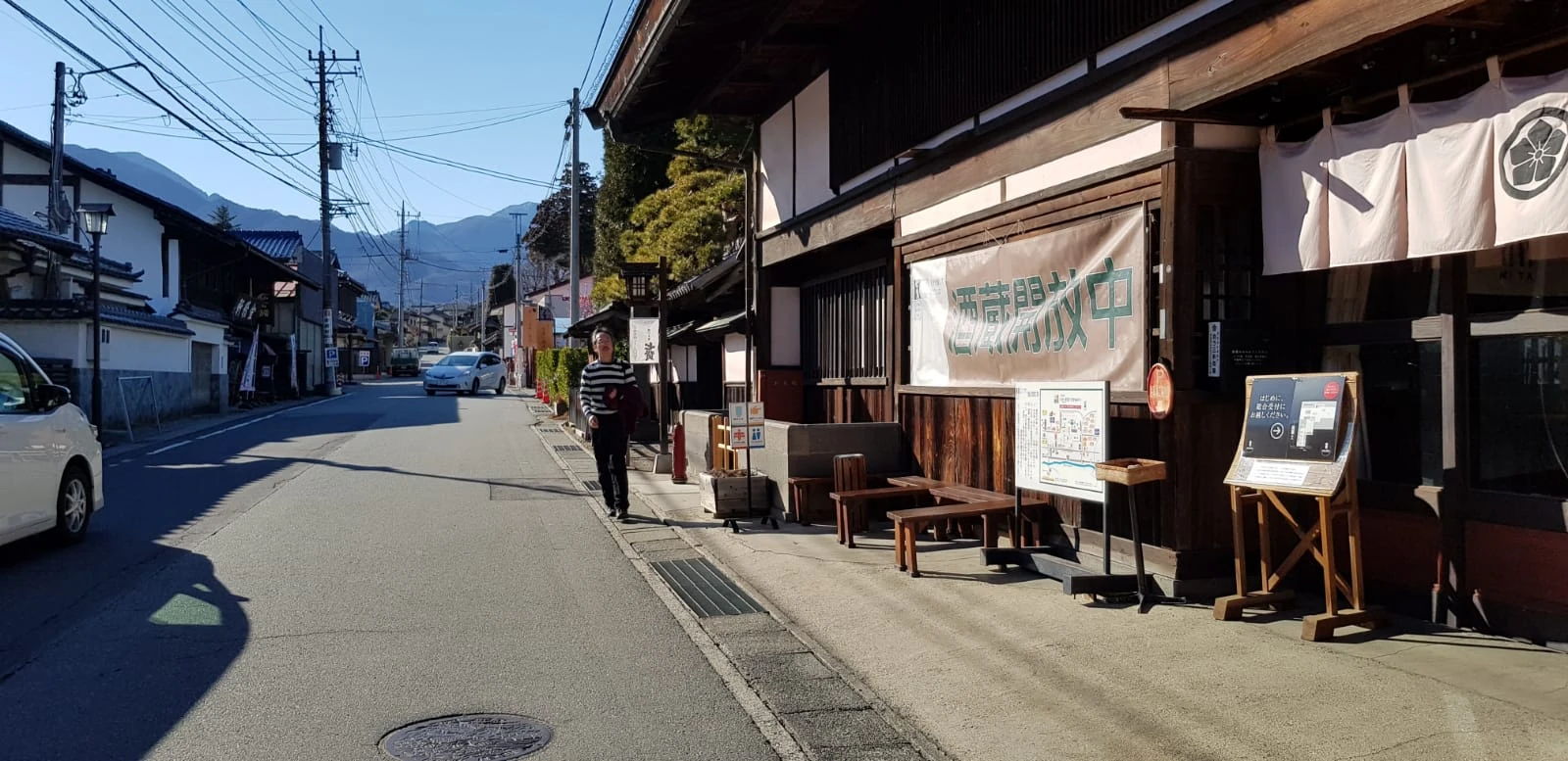 A quiet street of traditional Japanese buildings with mountains in the distance.